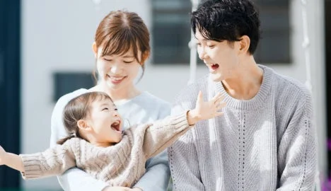 母親が子供を抱き、父親も一緒に笑っている幸せそうな家族の様子