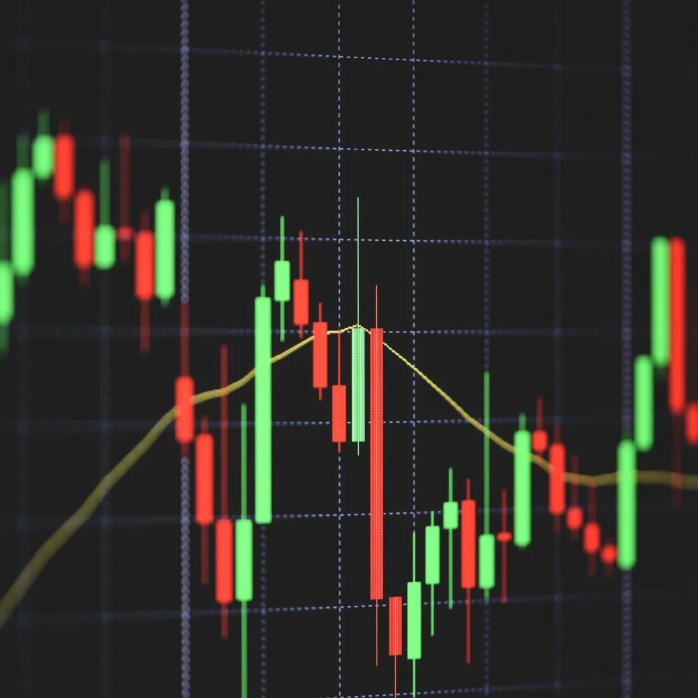暗い背景にグリッド線が引かれた画面に、赤と緑のローソク足と黄色の移動平均線が表示された株価チャートです。