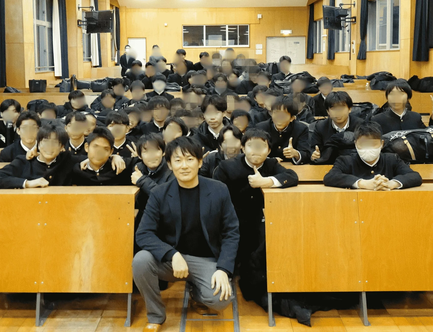 制服を着た大勢の学生たちが男性の大人と一緒に集合写真に収まっている様子