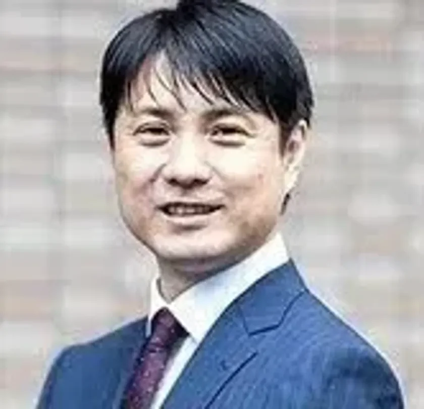 紺色のスーツとネクタイを着用し、穏やかに微笑むアジア系の男性のポートレートです。ビジネスシーンに適した表情で、プロフェッショナルな印象を与えます。