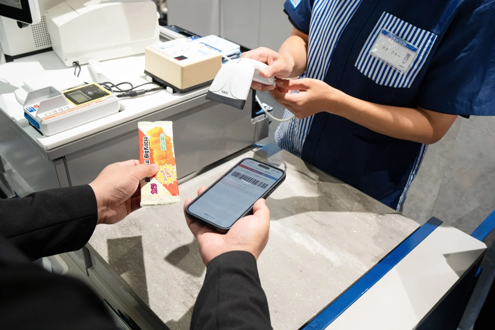 コンビニのレジでスマートフォン決済をする様子